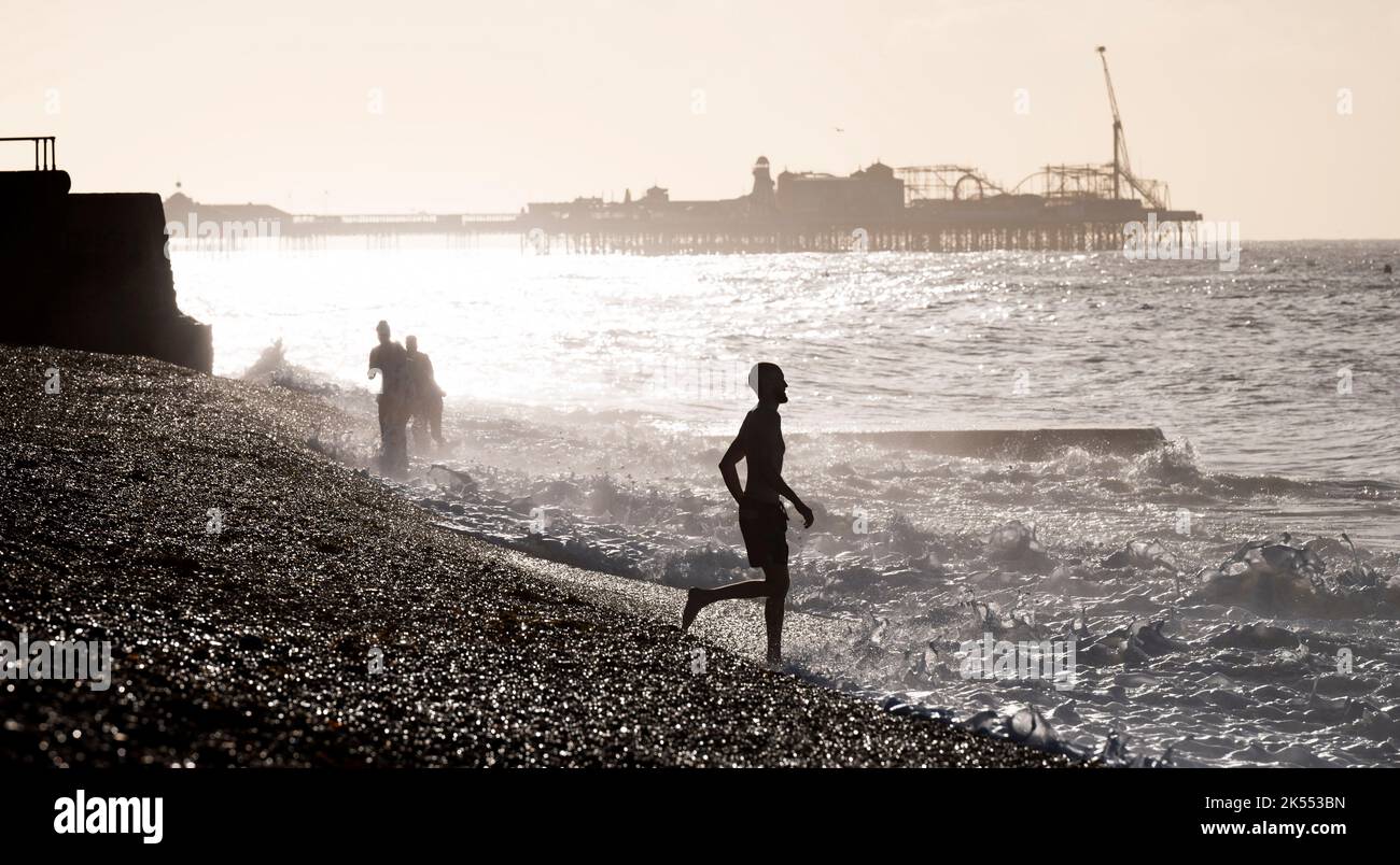 Brighton UK 6th ottobre 2022 - i nuotatori godono di una bella mattina soleggiata ma fredda a Brighton come le onde rotolare sulla spiaggia : Credit Simon Dack / Alamy Live News Foto Stock