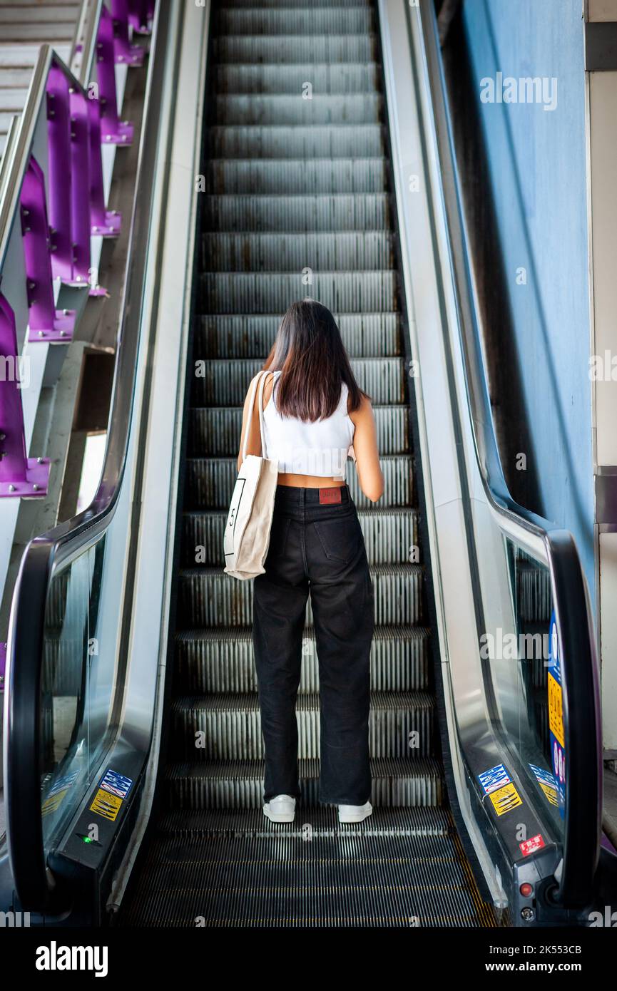 I passeggeri salgono la scala mobile fino alla stazione del treno sopraelevato BTS di Bangkok, Thailandia. Foto Stock