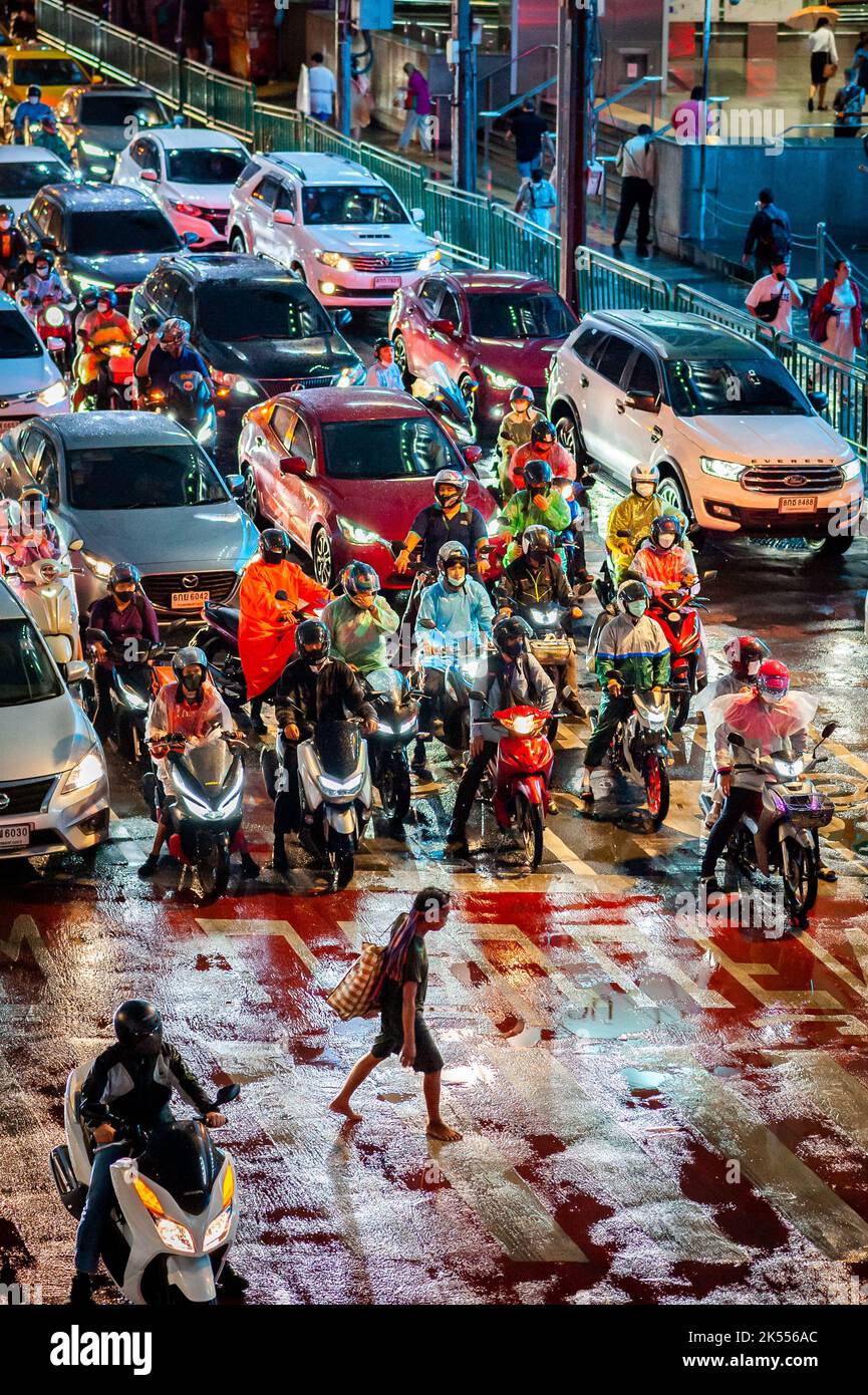 I pedoni attraversano il famoso incrocio di Asoke attraversando la zona pedonale in una notte molto piovosa a Bangkok in Thailandia. Foto Stock