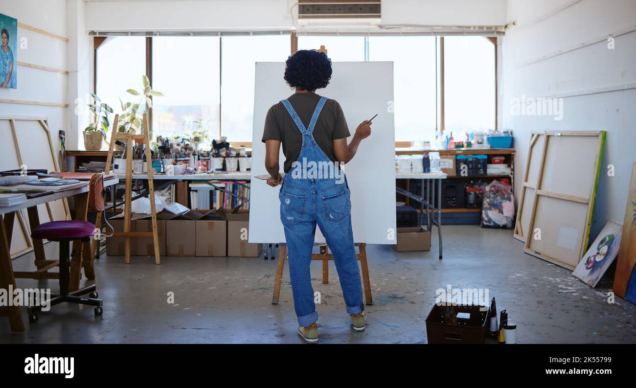 Donna artista nel suo studio, pittura arte, guardando la tela per ispirazione per dipingere nuovo progetto. Giovane pittore indiano creativo che lavora in lei Foto Stock