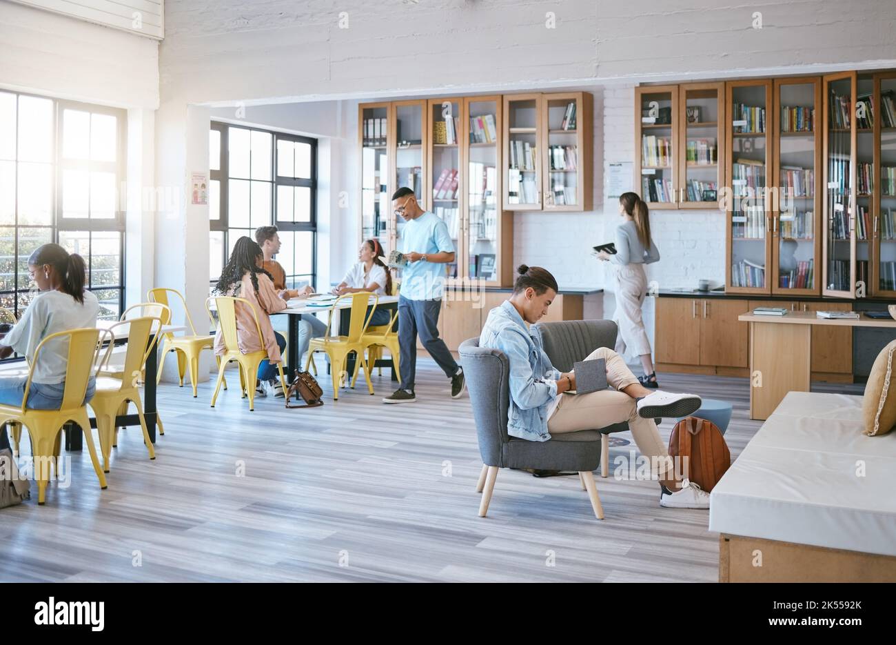 Istruzione, studenti e apprendimento in biblioteca presso l'università in relax, funky e creativa sala di studio. Diversità, università e studenti nello spazio sociale Foto Stock