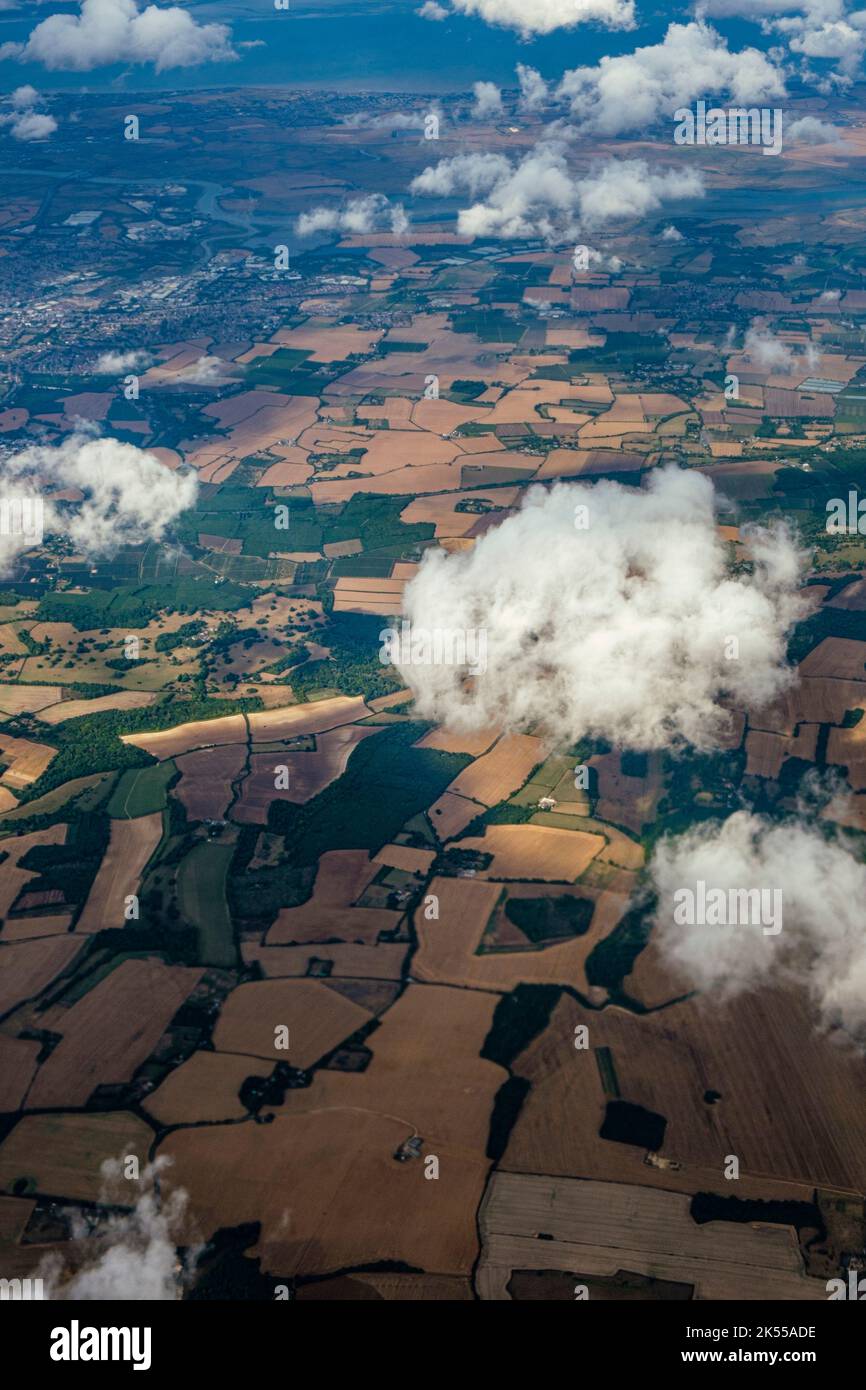 Guardando verso il basso sulle nuvole e la campagna rurale da una finestra di un aeromobile passeggeri. Foto Stock