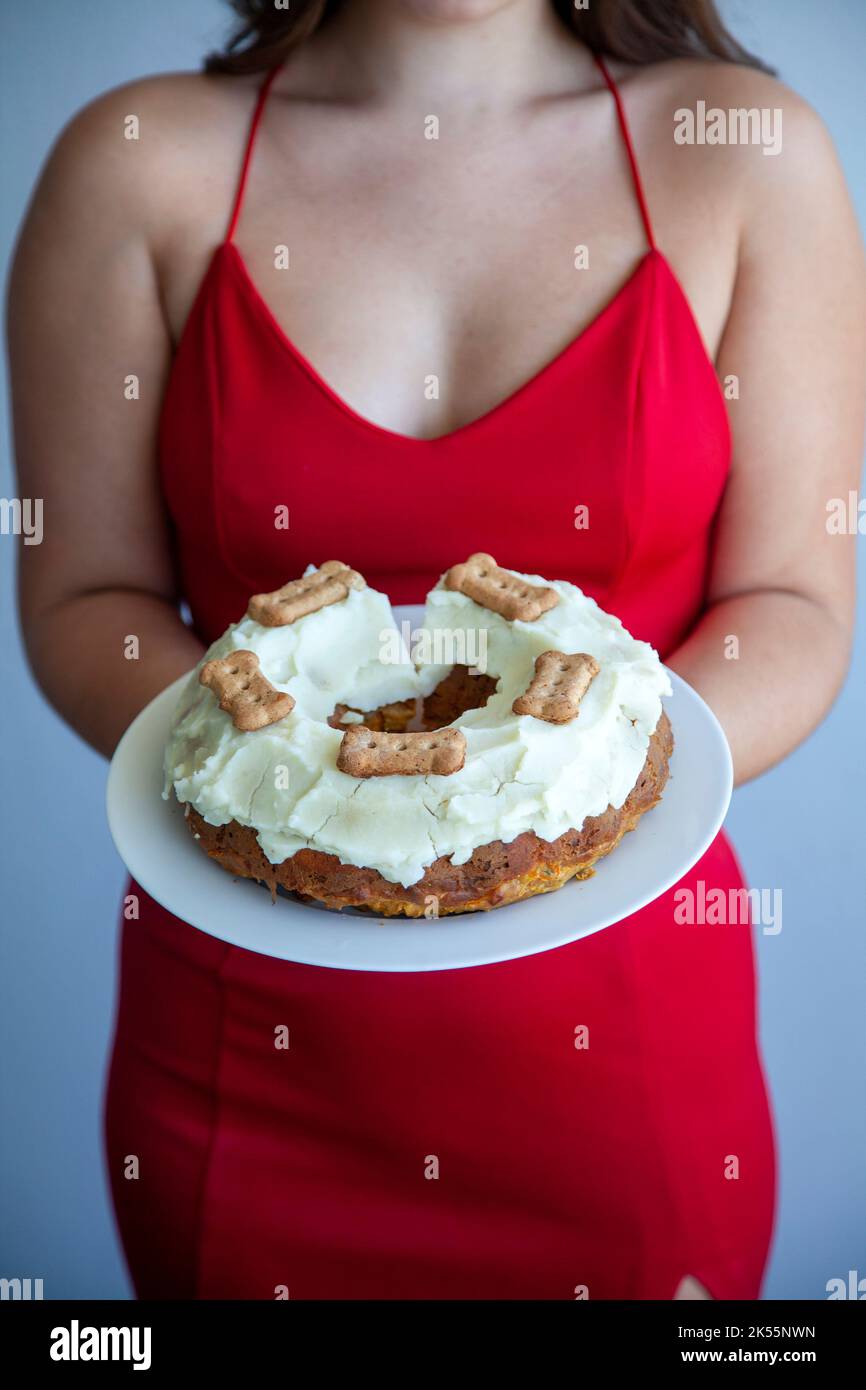 Donna che tiene burro di arachidi e torta di carote con patata e yogurt glassa per cane Foto Stock