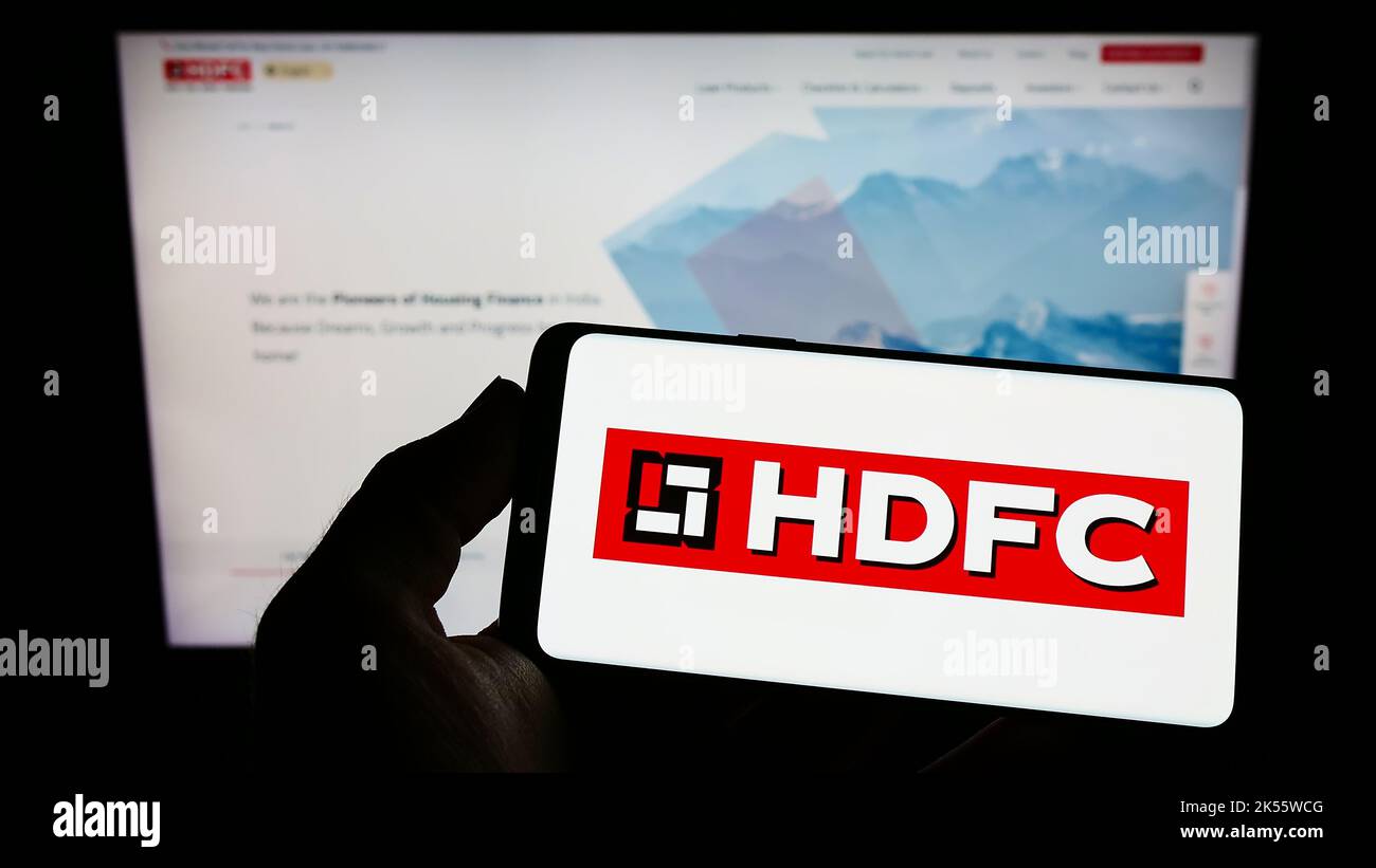Persona che tiene in mano uno smartphone con il logo di Housing Development Finance Corporation (HDFC) sullo schermo di fronte al sito Web. Messa a fuoco sul display del telefono. Foto Stock