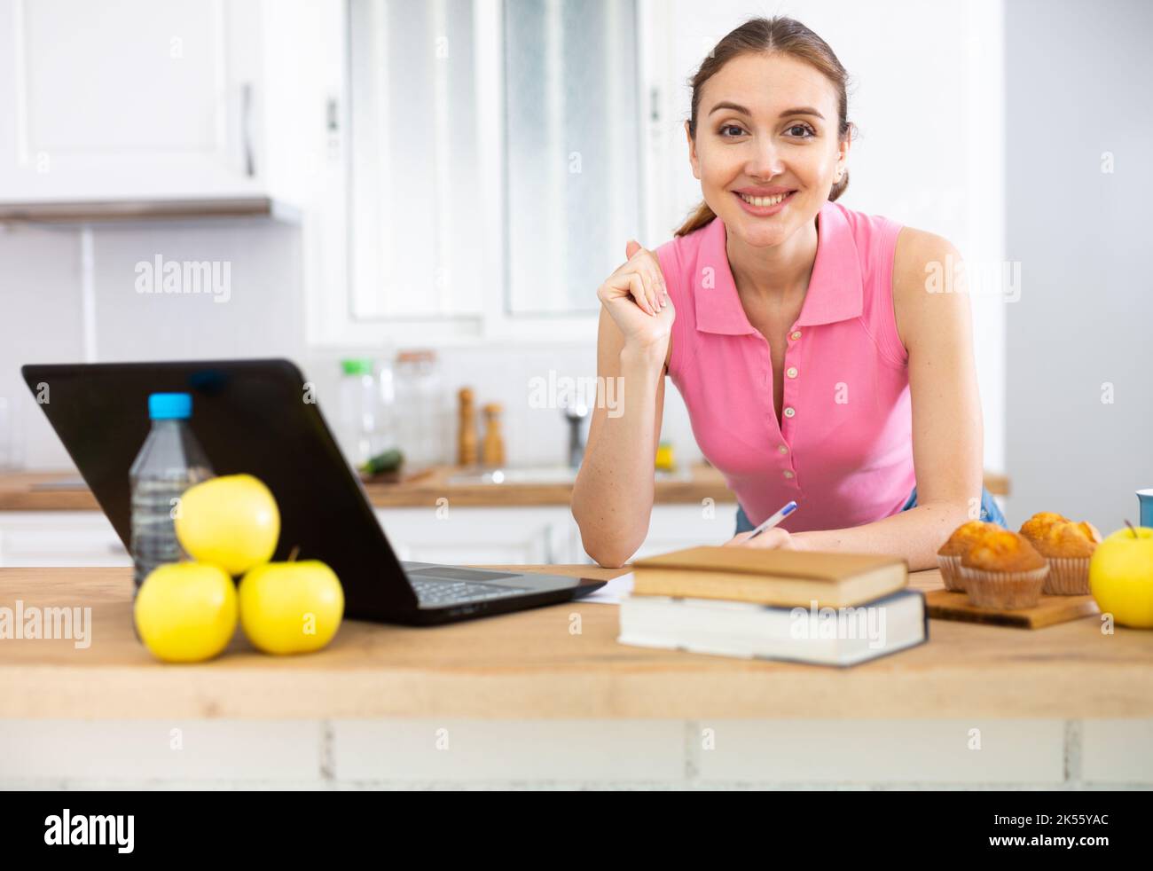 Donna cuoco legge la ricetta in computer portatile e cucina insalata in cucina Foto Stock