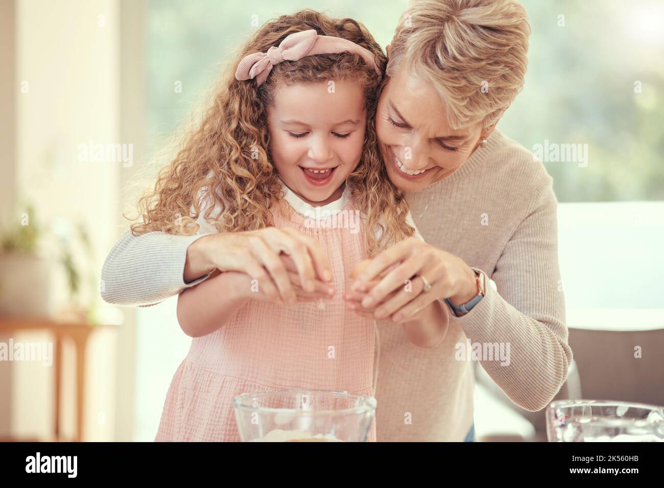 I bambini, la famiglia e la cottura con una ragazza che impara e la nonna che cucinano in una cucina della loro casa insieme. Bambini, cibo e ingredienti con un anziano Foto Stock