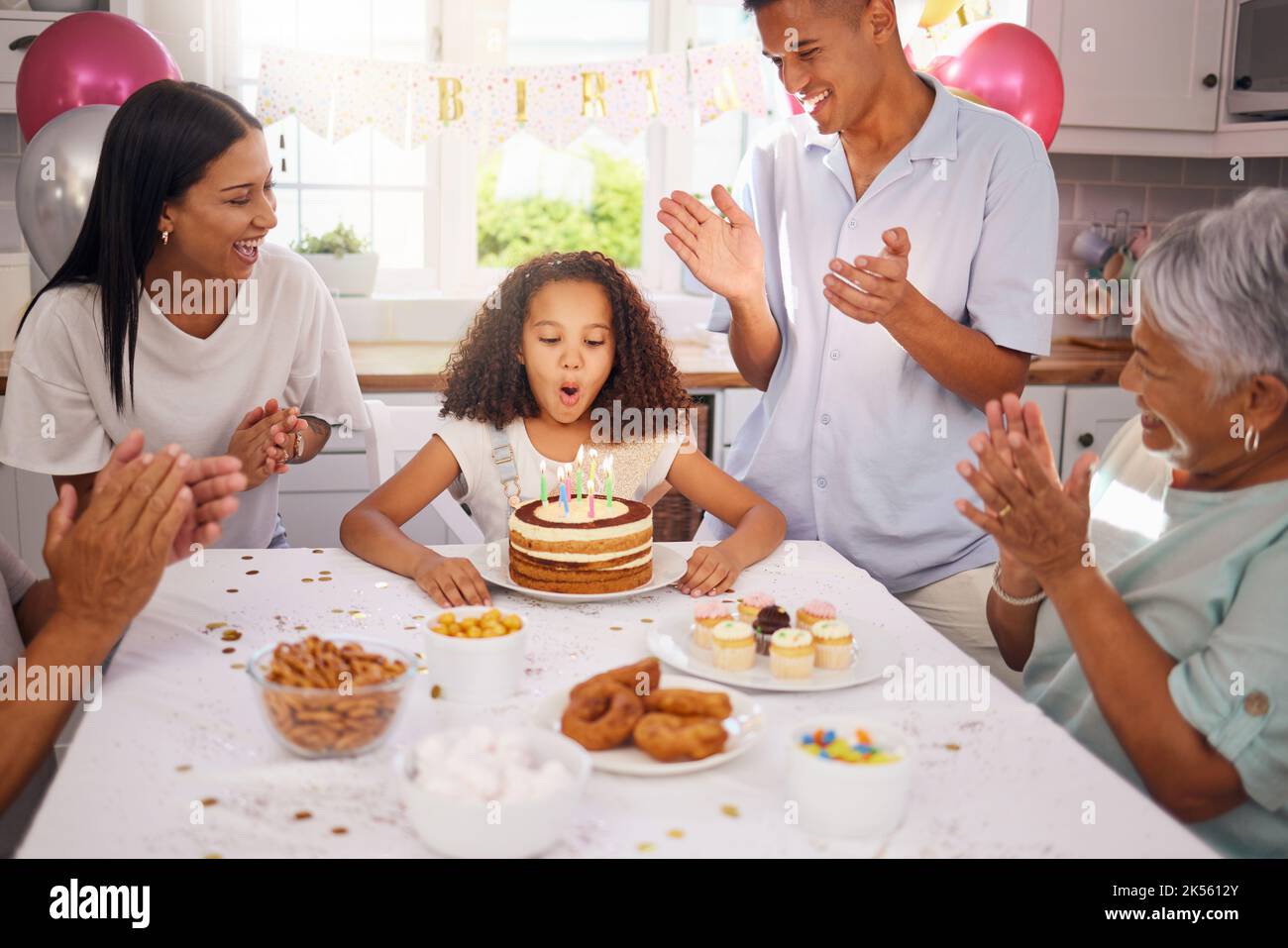 Compleanno, bambini e torta con una ragazza in festa con la famiglia durante una festa mentre soffiando le sue candele per fare un desiderio. Ragazzi, applausi e felici Foto Stock