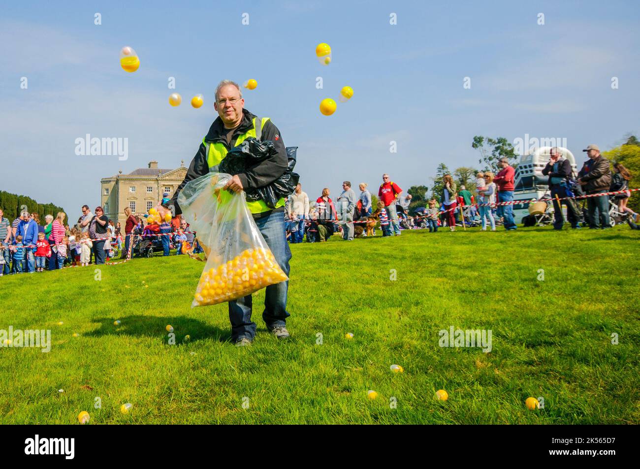 Strangford, Irlanda del Nord. 21 Apr 2014 - Un uomo lancia uova di plastica contenenti uova di cioccolato in preparazione come il National Trust tenere una caccia alle uova di Pasqua per i bambini di 1-4 anni a Castle Ward Foto Stock
