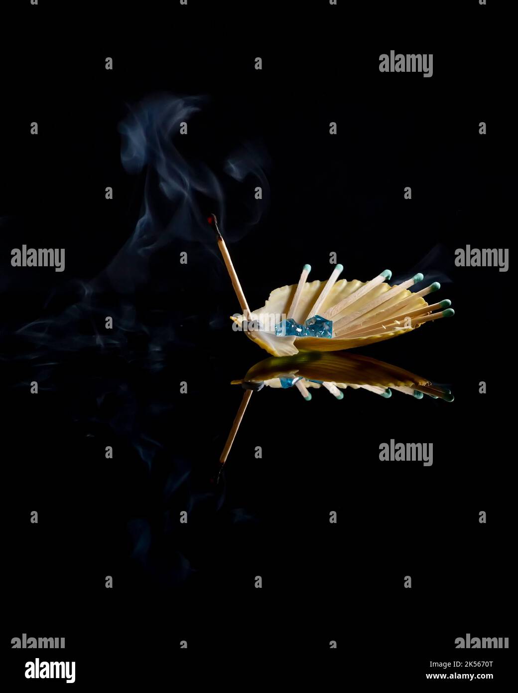 Alcuni fiammiferi, uno dei quali è stato appena estinto con il fumo su di esso, sono collocati all'interno di un guscio di capesante Foto Stock