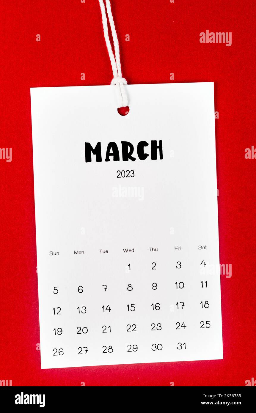 Marzo 2023 pagina del calendario appeso su corda bianca su sfondo rosso. Foto Stock