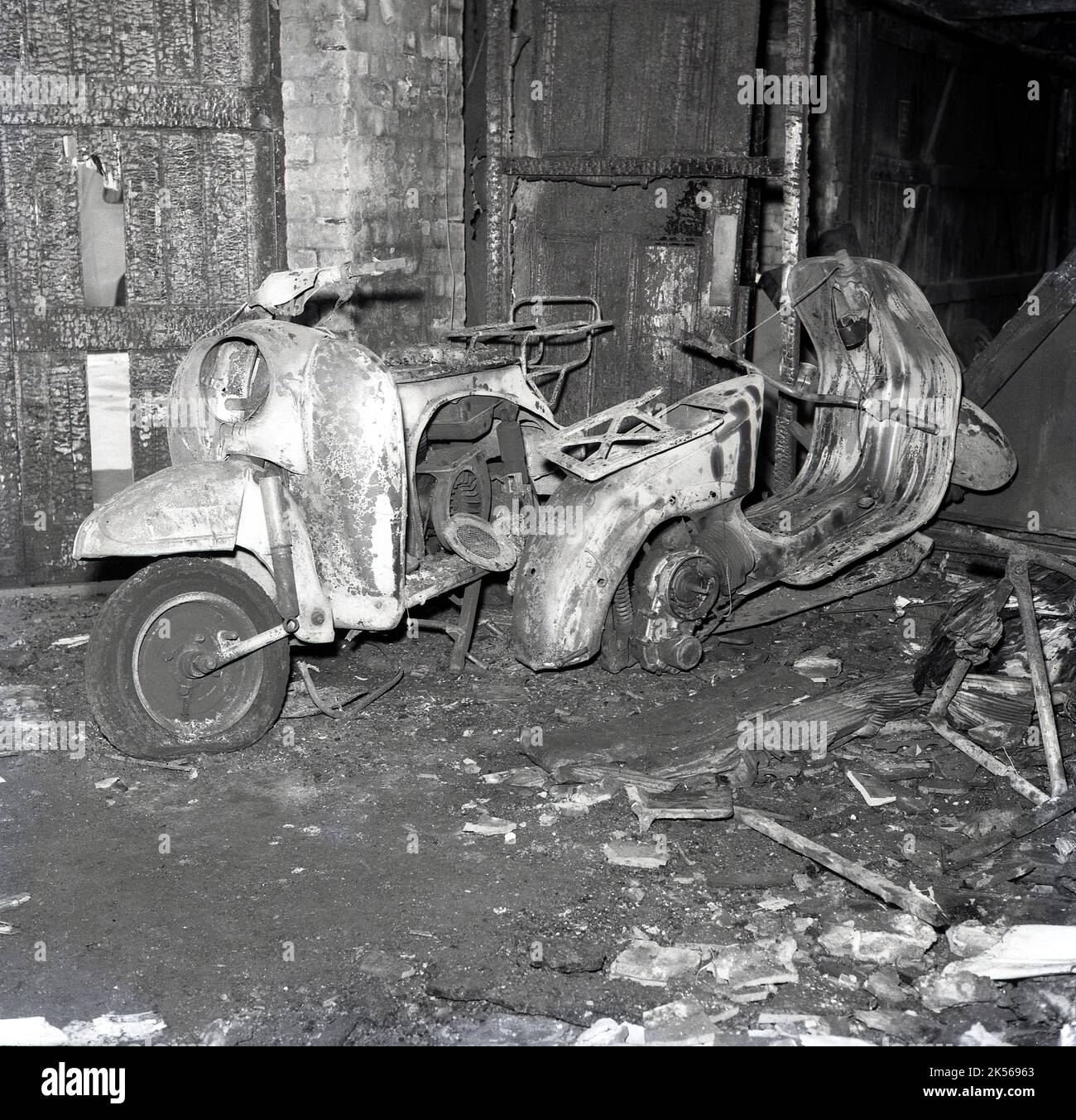 1964, storico, due scooters motori bruciati, gravemente danneggiati, a seguito di un incendio in un magazzino, Inghilterra, Regno Unito. Foto Stock