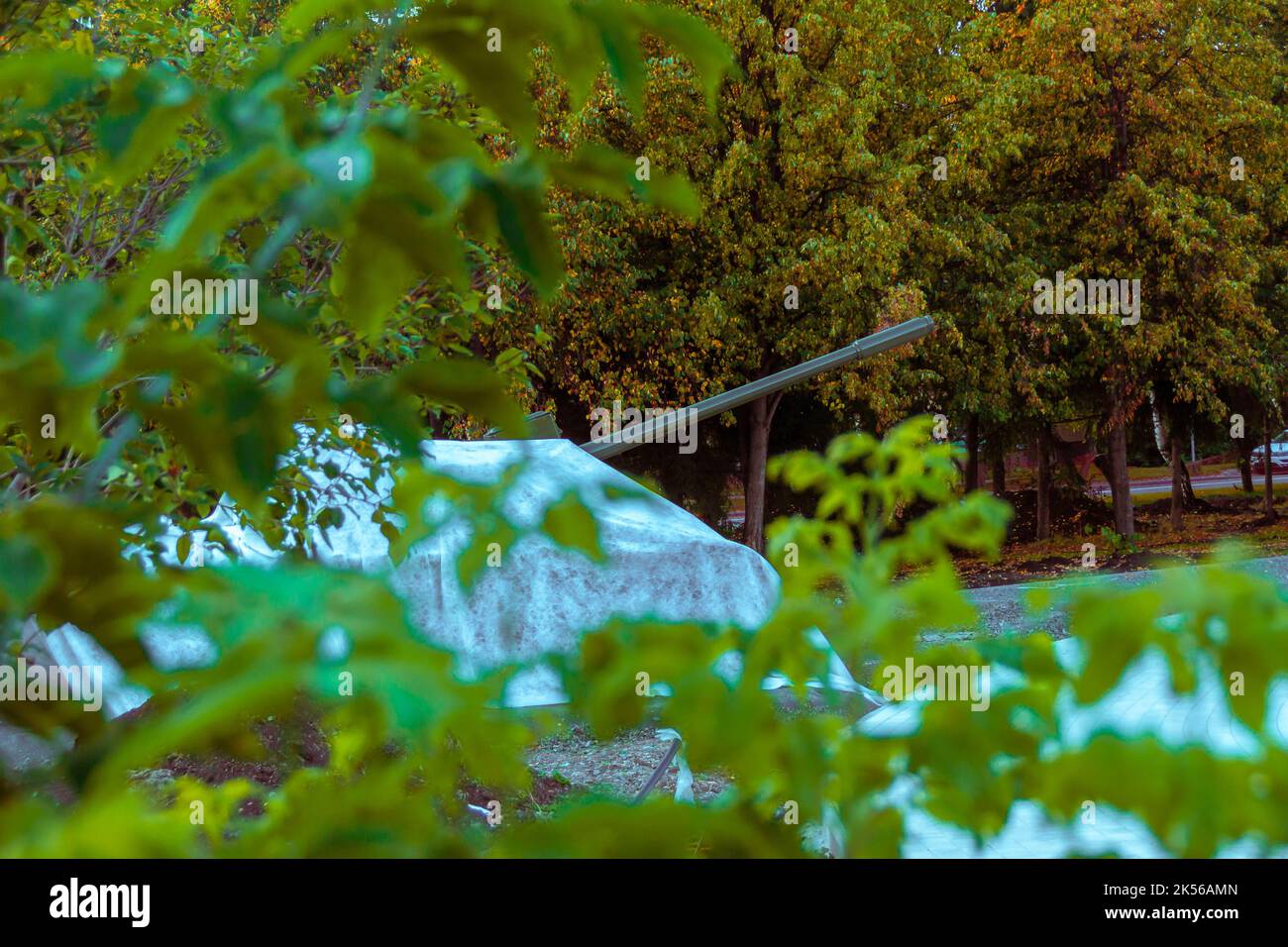 attrezzature militari fotografate da lontano dietro alberi ricoperti di materiale grigio, fuoco selettivo Foto Stock