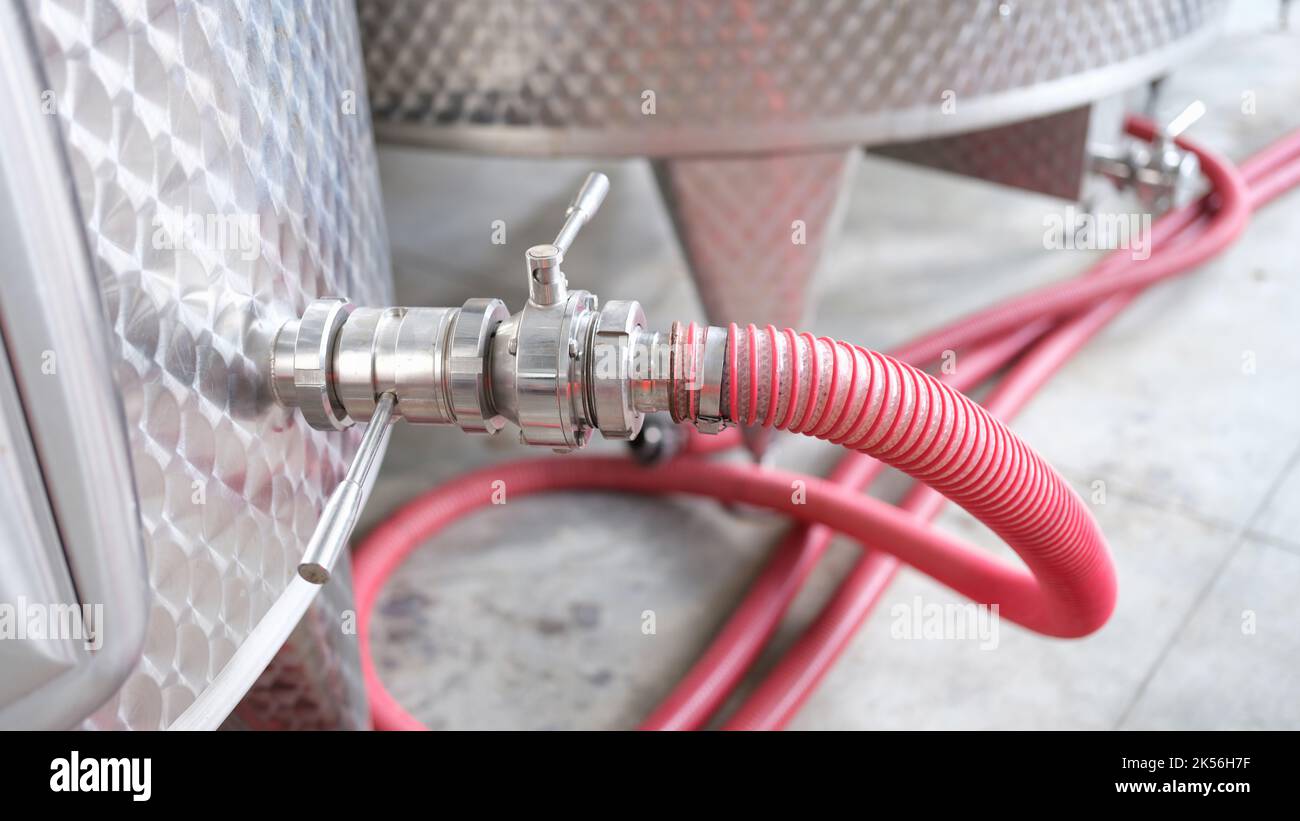 Rubinetto in acciaio inox con tubo flessibile su grandi vasche metalliche in produzione Foto Stock