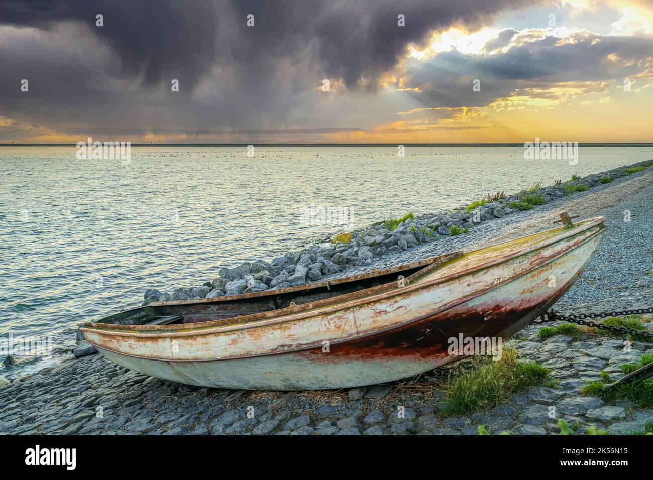 Barca a remi su scivolo con meccanismo di sollevamento lungo la diga Del Ijsselmeer con le nuvole di pioggia di colore rosso che scivola sopra il lago Foto Stock