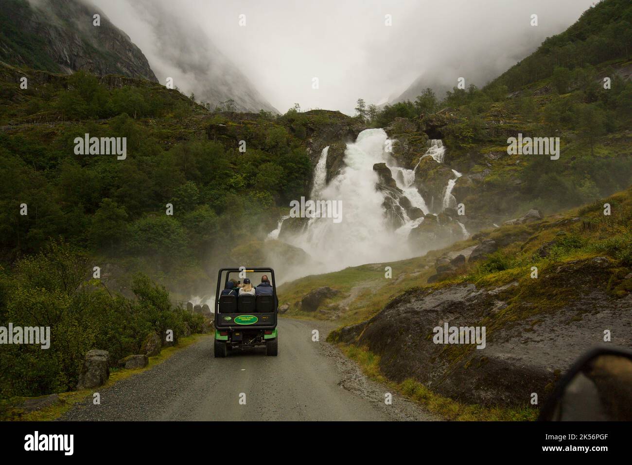 Turismo trasportato al ghiacciaio Briksdal, Briksdalsbreen, in troll cart, troll car, navetta per il ghiacciaio. Guida verso una cascata. Briksdalsbre. Foto Stock