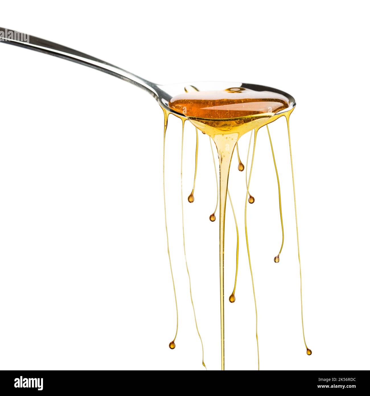 Miele che sgocciola dal cucchiaio con goccioline, isolato su bianco. Foto Stock