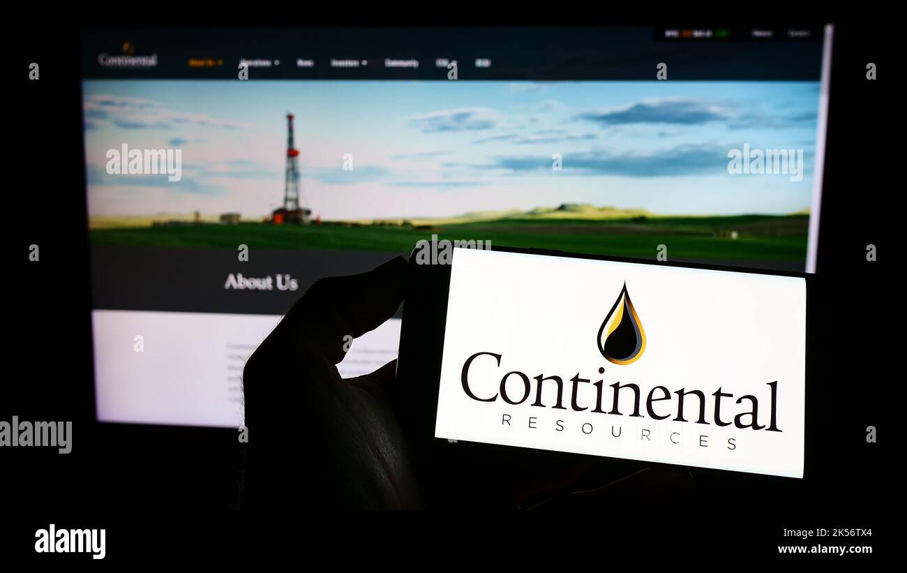 Persona che detiene il telefono cellulare con il logo della società petrolifera statunitense Continental Resources Inc. Sullo schermo di fronte alla pagina Web. Messa a fuoco sul display del telefono. Foto Stock