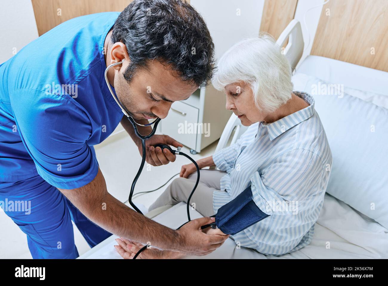 medico con stetoscopio misura la pressione di paziente anziano con tonometro al reparto ospedaliero. Prevenzione e trattamento dell'ipertensione Foto Stock
