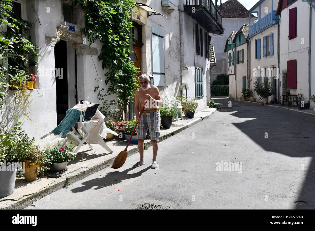 L'uomo francese che scava la strada fuori casa nel villaggio storico di Salies-de-Bearn, Francia Foto Stock