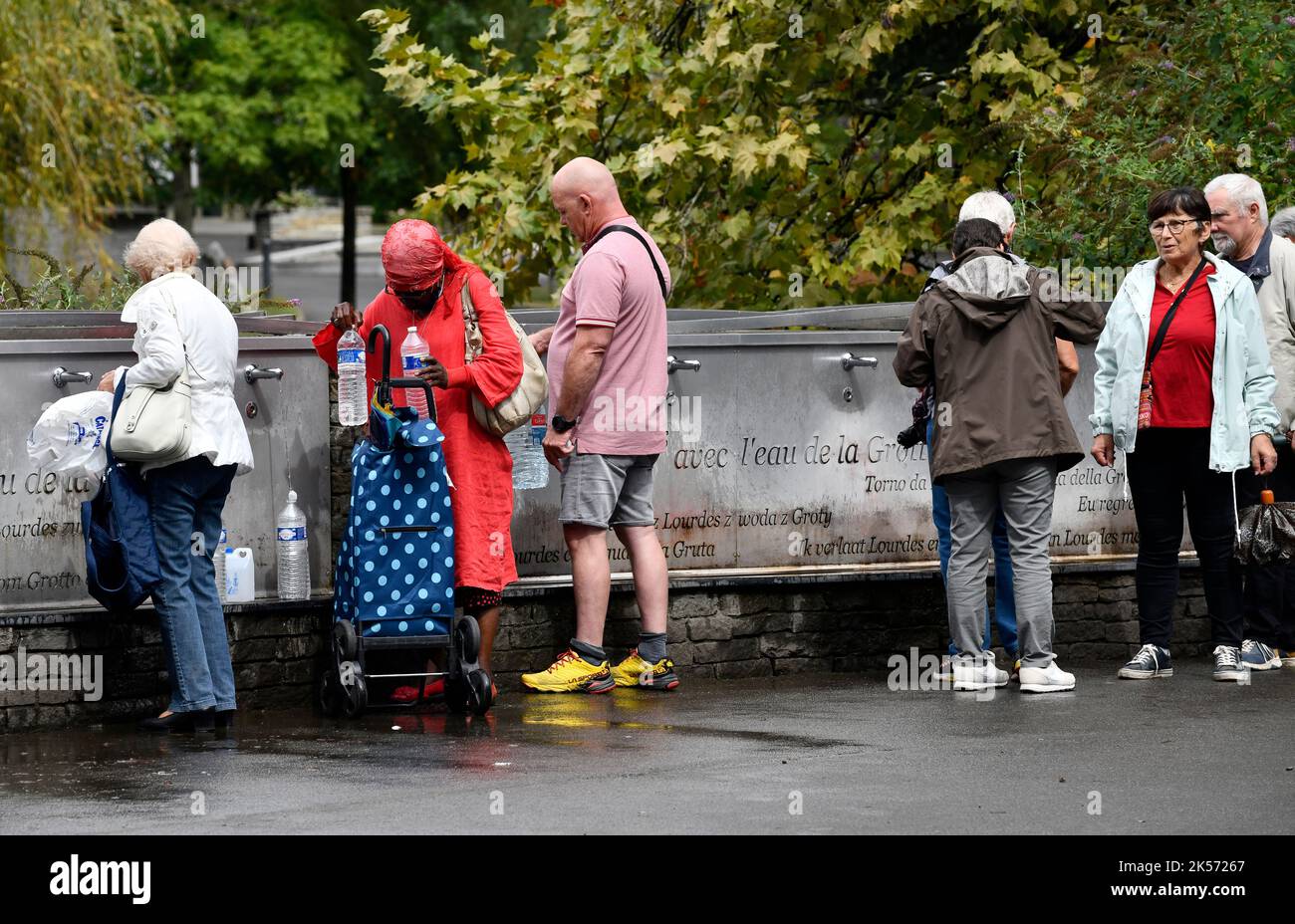 Lourdes, alti Pirenei, Francia. Pellegrini cristiani che raccolgono l'acqua di Lourdes che scorre dalla Grotta di Massabielle nel Santuario di nostra Signora o Foto Stock