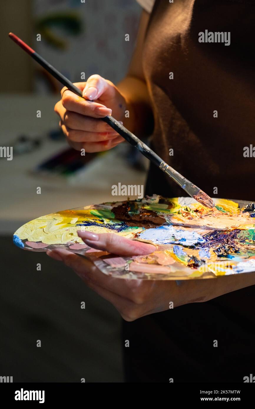Scuola di pittura. Master class femminile. Hobby artistico. Donna irriconoscibile che tiene tavolozza con colori e pennello pronto per la creazione di opere d'arte i Foto Stock