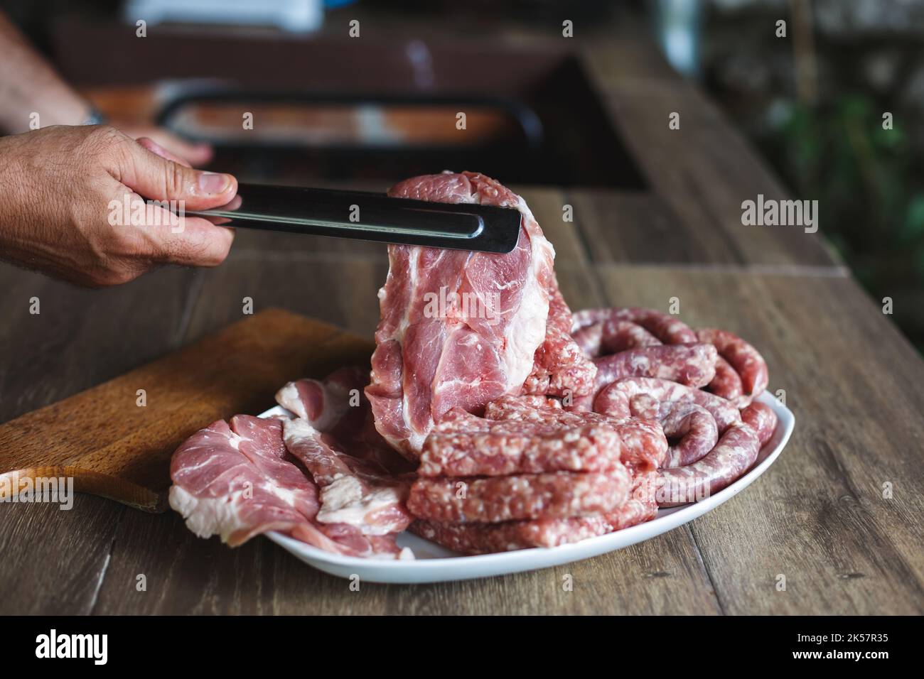 Uomo che prepara la cena con carne fresca, primo piano. Mani che tengono bistecca di filetto crudo all'aperto. Pronto per il barbecue. Messa a fuoco selettiva, spazio di copia Foto Stock