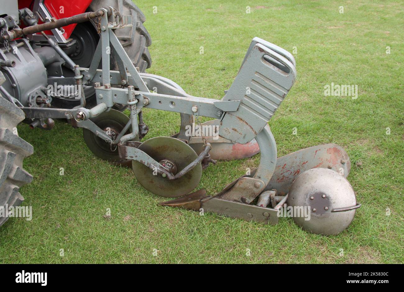 Un aratro vintage sul retro di un trattore agricolo. Foto Stock