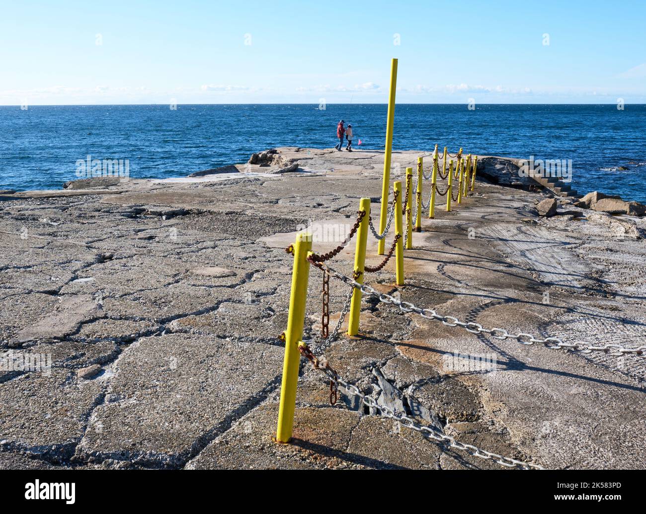 I pali gialli della recinzione segnano il bordo di un molo a Port Erin, Isola di Man. Foto Stock