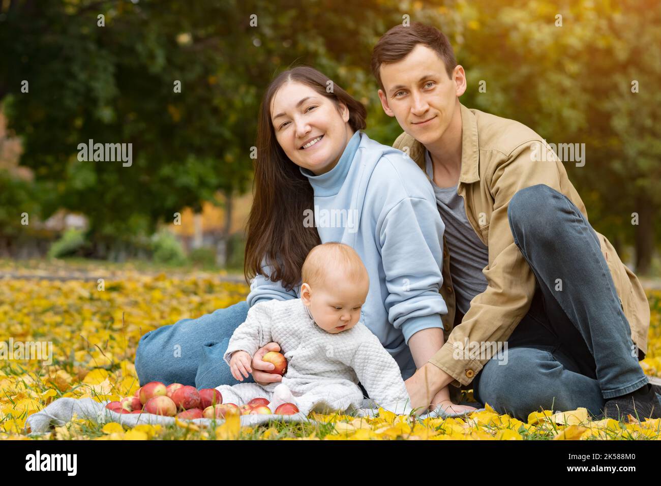 La giovane famiglia si propone per la fotosessione autunnale in un parco colorato Foto Stock