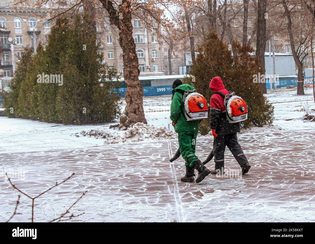 Dnepropetrovsk, Ucraina - 02.04.2022: Lavoro stagionale delle utenze cittadine nel parco. Un lavoratore con una soffiante motorizzata zaino soffia la neve da un parco pa Foto Stock Dnepropetrovsk, Ucraina - 02.04.2022: Lavoro stagionale delle utenze cittadine nel parco. Un lavoratore con una soffiante motorizzata zaino soffia la neve da un parco pa Foto Stock