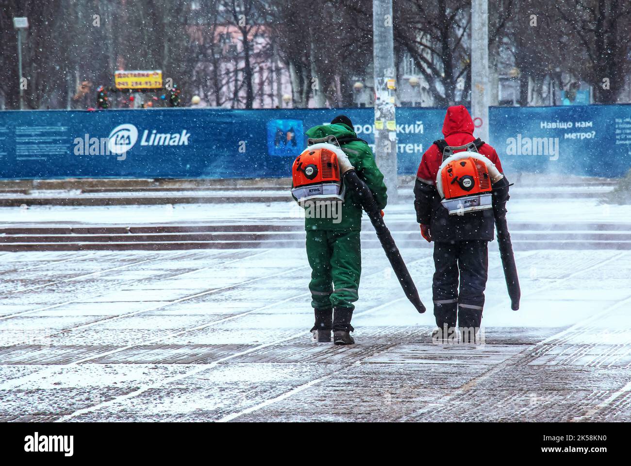 Dnepropetrovsk, Ucraina - 02.04.2022: Lavoro stagionale delle utenze cittadine nel parco. Un lavoratore con una soffiante motorizzata zaino soffia la neve da un parco pa Foto Stock Dnepropetrovsk, Ucraina - 02.04.2022: Lavoro stagionale delle utenze cittadine nel parco. Un lavoratore con una soffiante motorizzata zaino soffia la neve da un parco pa Foto Stock