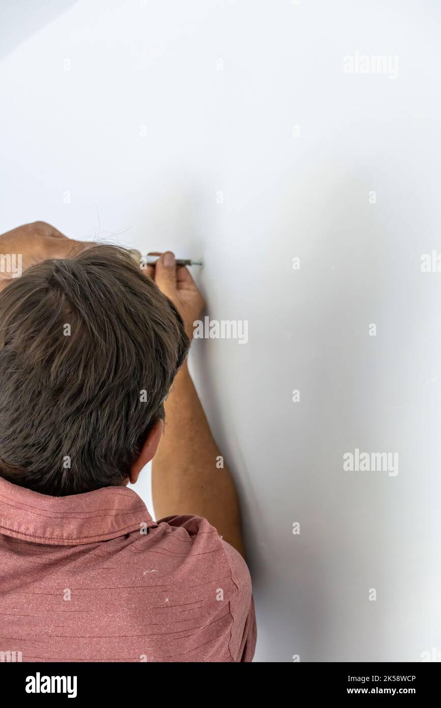 uomo che svita una vite con una mano o un cacciavite manuale, uomo anziano, latino ispanico Foto Stock