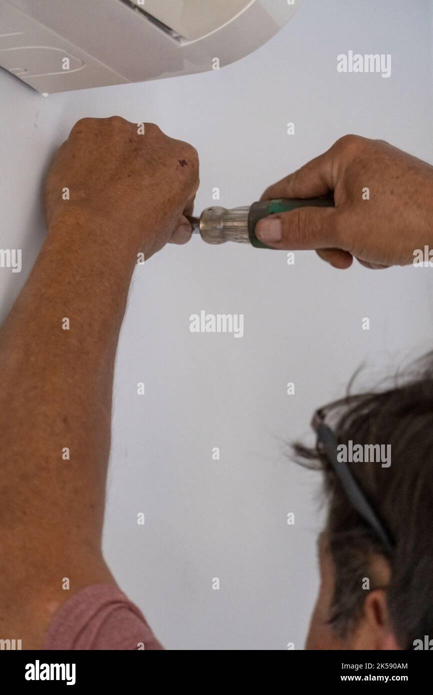 uomo che svita una vite con una mano o un cacciavite manuale, uomo anziano, latino ispanico Foto Stock