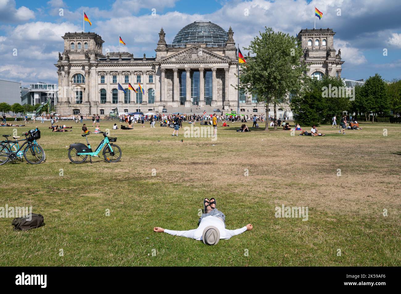 23.07.2022, Germania, Berlino - la gente si trova sul prato di fronte al Reichstag, il Platz der Republik nel quartiere Mitte, godendosi un'estate soleggiata Foto Stock