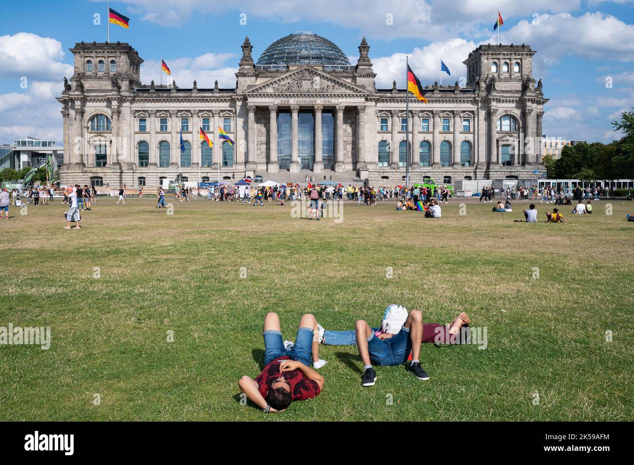 23.07.2022, Germania, Berlino - la gente si trova sul prato di fronte al Reichstag, la Piazza della Repubblica nel quartiere Mitte, godendo di una giornata estiva di sole Foto Stock
