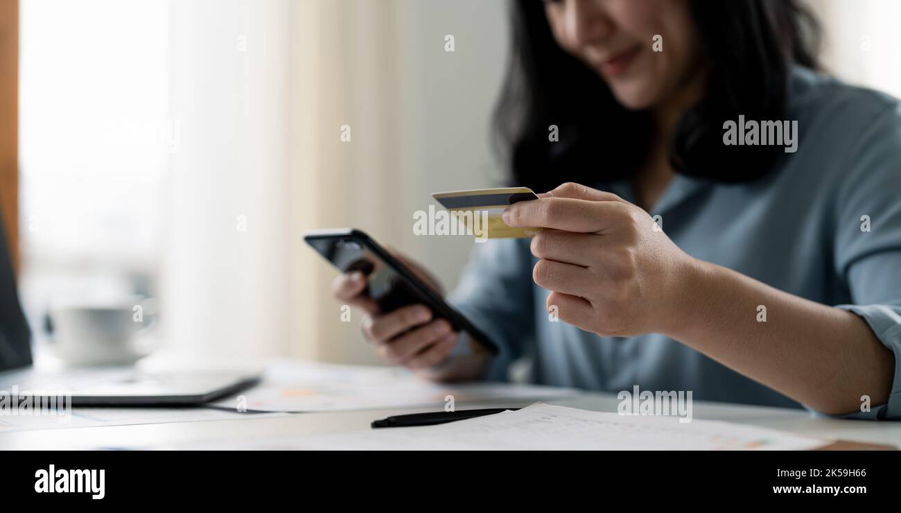donna che tiene la carta di credito con l'uso dello smartphone per lo shopping online mentre effettua gli ordini a casa. lavoro, stile di vita, tecnologia, e-commerce Foto Stock