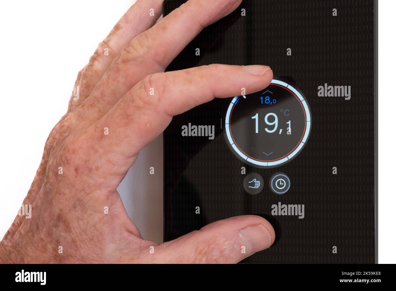 La mano fa ruotare il termostato dell'impianto di riscaldamento un po' più in basso o più in alto. Aumento dei prezzi dell'energia. Isolato su sfondo bianco Foto Stock