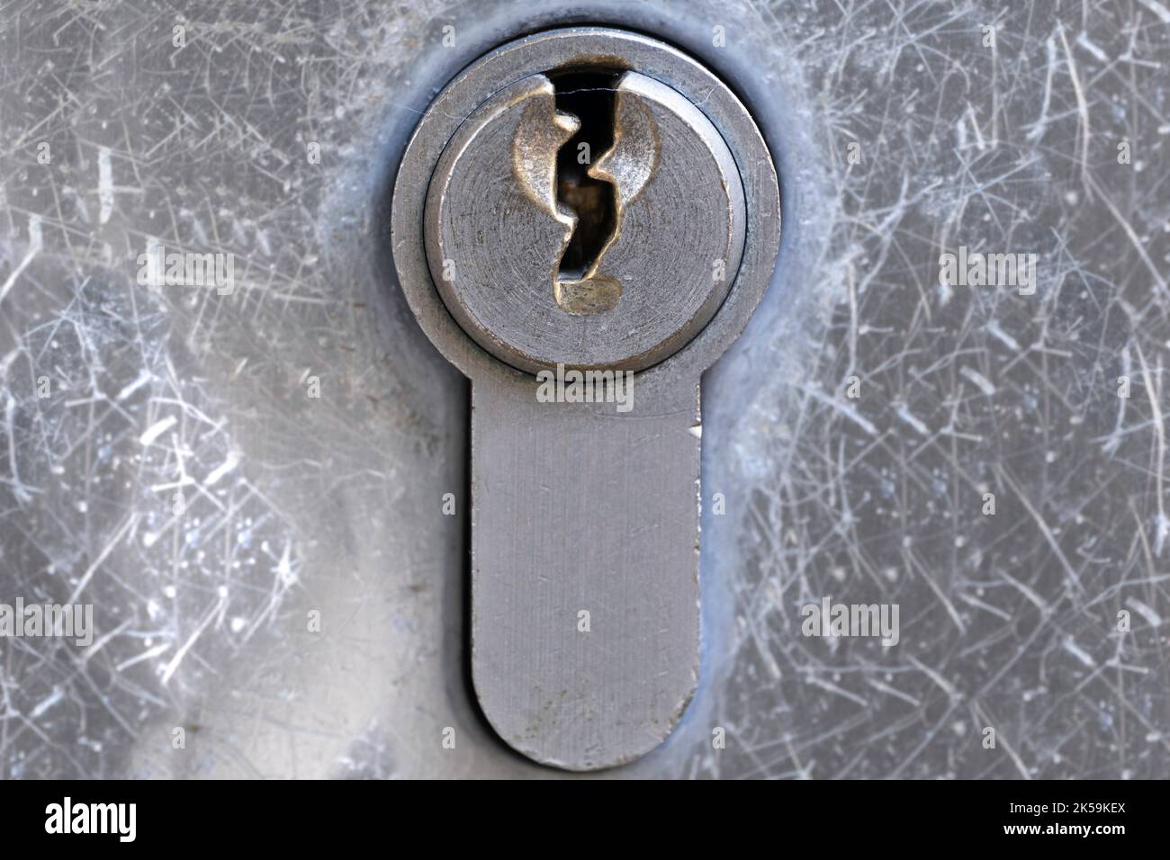 Piastra di metallo con foro per chiave di una serratura a cilindro in una porta. Isolato su sfondo grigio a grunge (metallo) Foto Stock