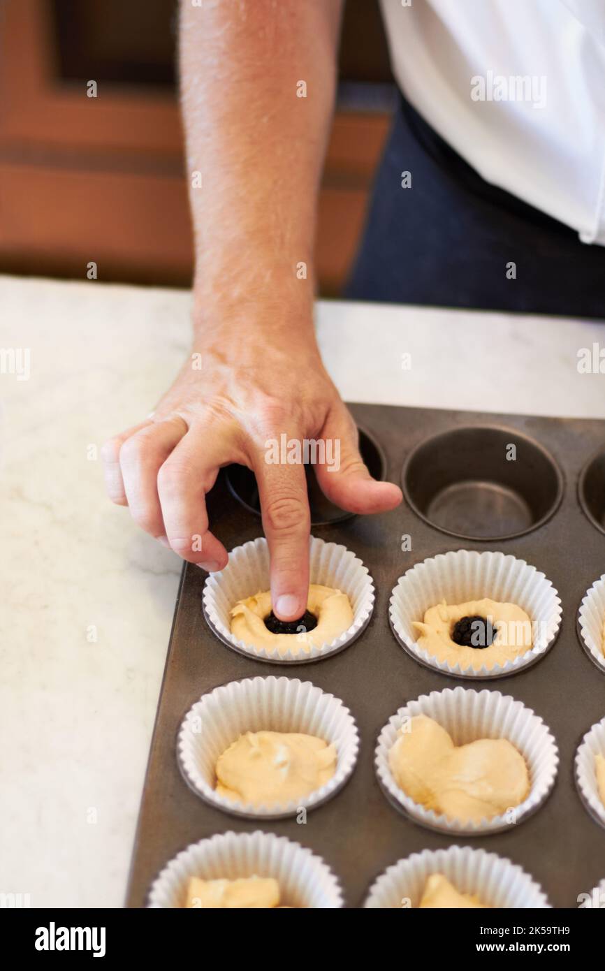Aggiungendo una piccola sorpresa deliziosa. Primo piano di un panettiere che mette un centro di cioccolato in un vassoio Foto Stock