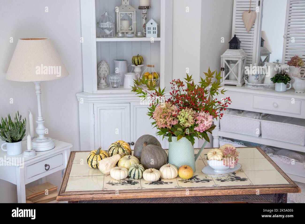 sistemazione autunnale con bouquet di fiori di ortensia, fianchi di rosa e foglie di acero e zucche Foto Stock