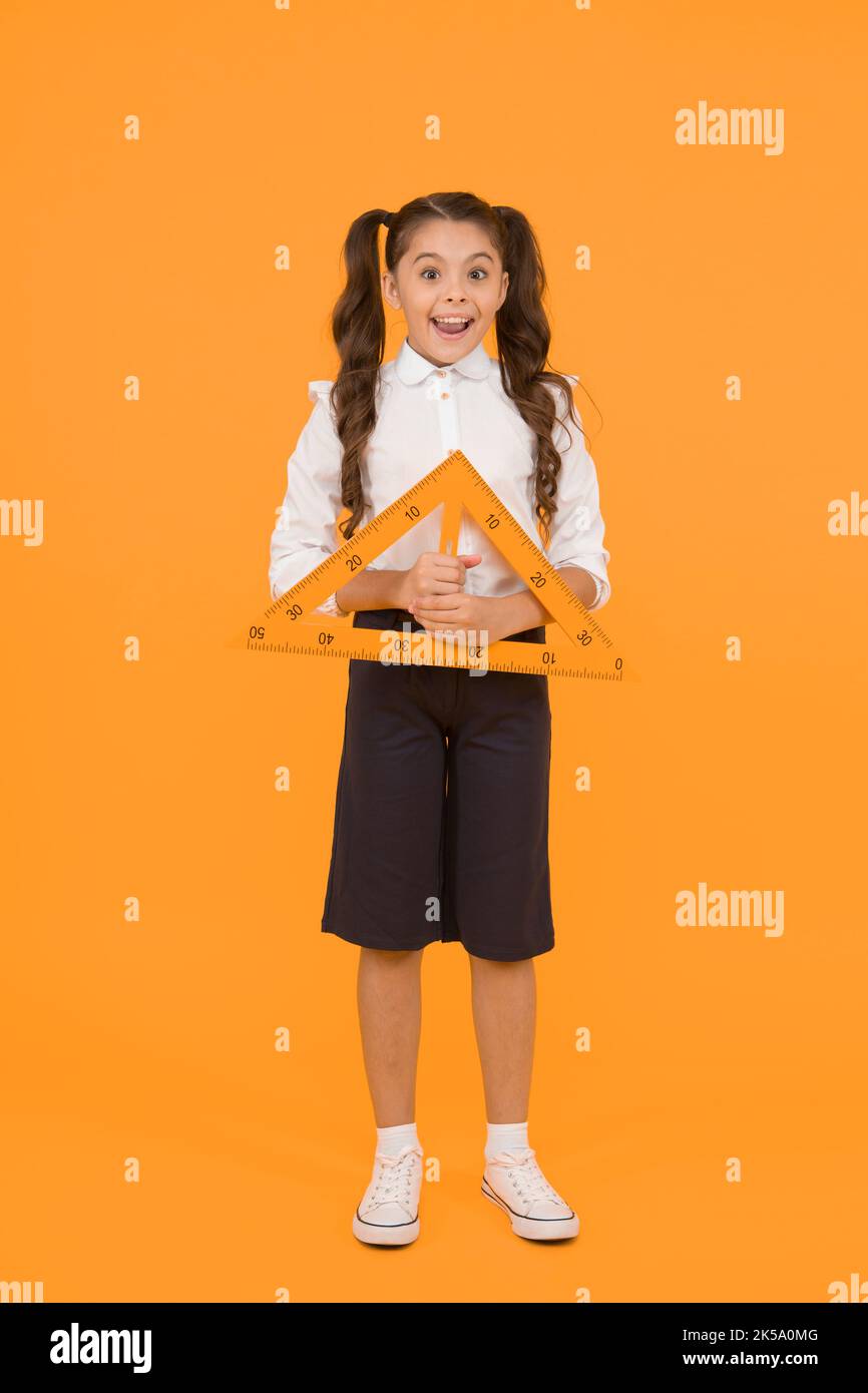 Apparecchiatura di misurazione. Bambino cute scuola studente di studio matematica. Angolo retto triangolare. Giornata della conoscenza. L'uniforme della scuola della scuola tiene la geometria grande del righello Foto Stock