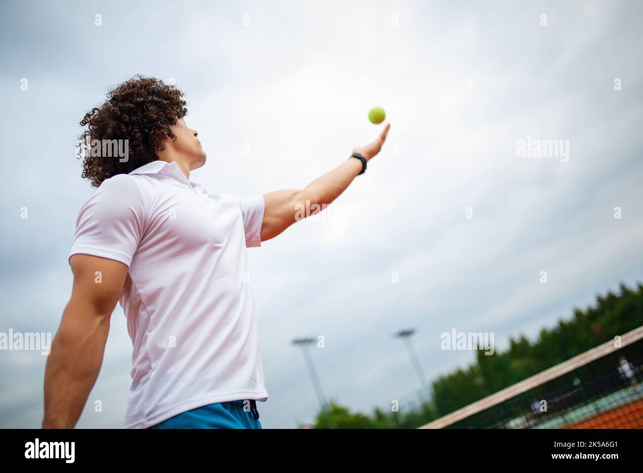 Il giovane bel tennista con racket e palla si prepara a servire all'inizio della partita o partita. Foto Stock