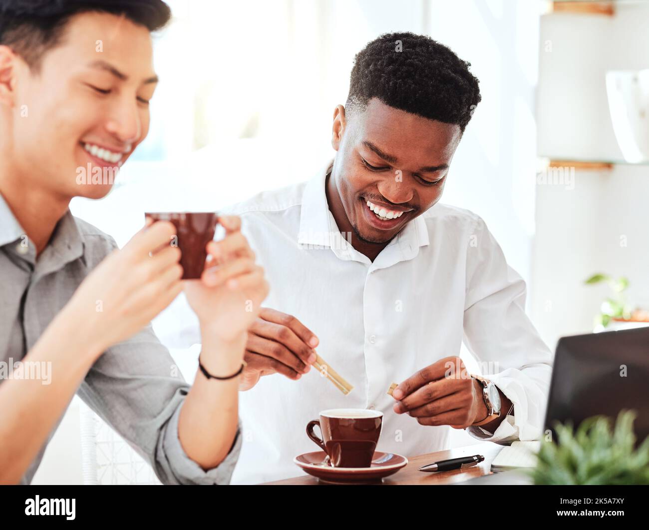 Riunioni di lavoro, uomini e caffè con computer portatile nel bar. Diversità, uomo nero e uomo asiatico in caffetteria, sorridente e bere tè su Foto Stock