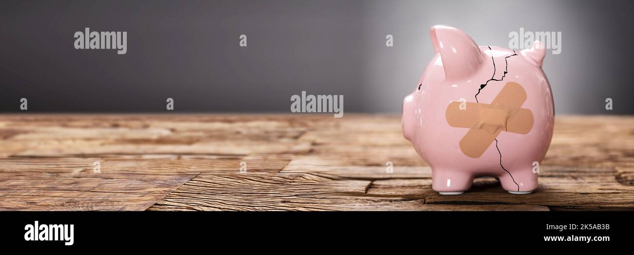 Piggy Bank con Band Aid. Gestione del debito monetario Foto Stock