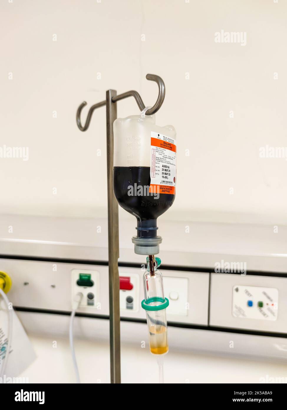 Primo piano del sacchetto di plastica per infusione endovenosa con camera di gocciolamento in sala risveglio presso l'unità di terapia intensiva dell'ospedale con sfondo bokeh. Nessuna gente. Foto Stock