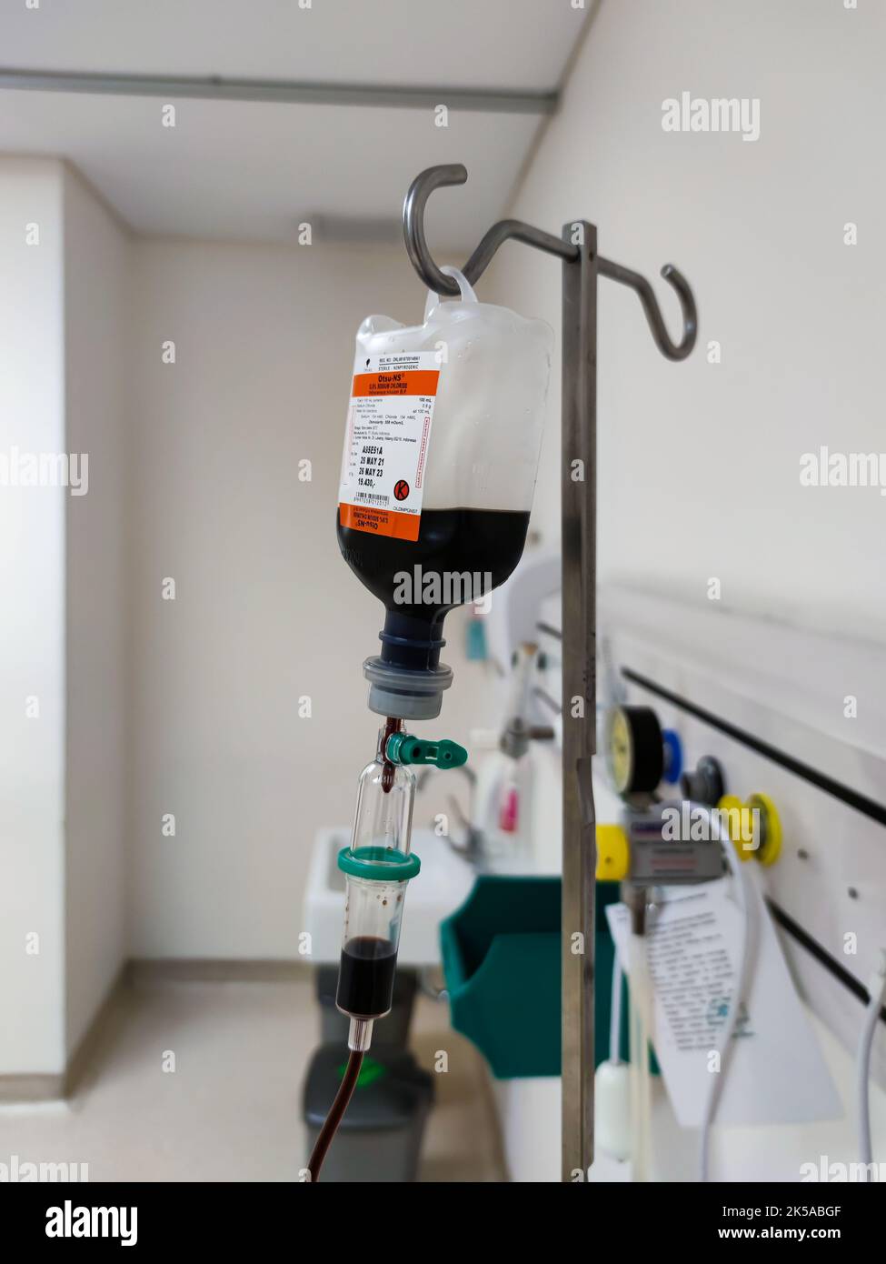 Primo piano del sacchetto di plastica per infusione endovenosa con camera di gocciolamento in sala risveglio presso l'unità di terapia intensiva dell'ospedale con sfondo bokeh. Nessuna gente. Foto Stock