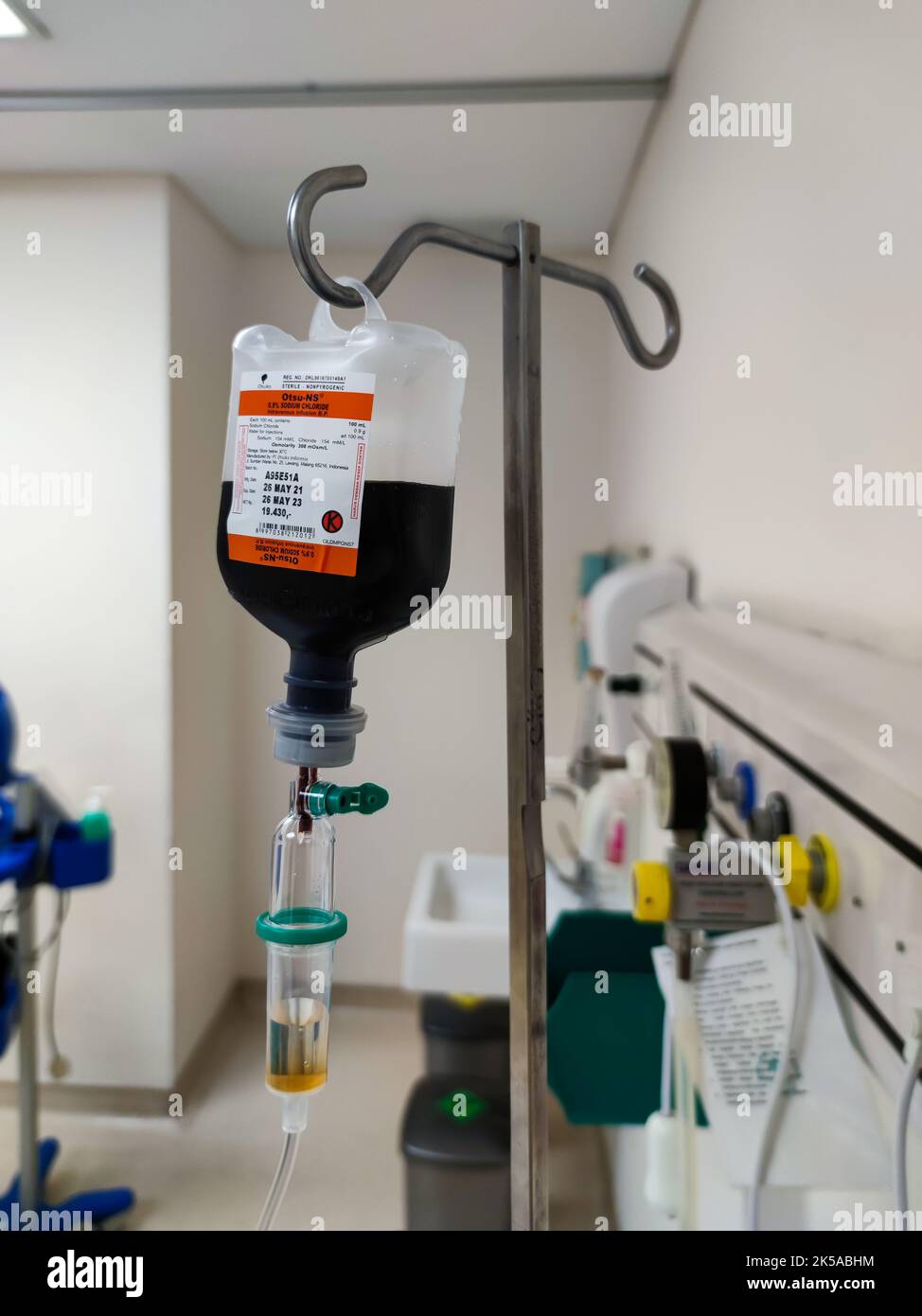 Primo piano del sacchetto di plastica per infusione endovenosa con camera di gocciolamento in sala risveglio presso l'unità di terapia intensiva dell'ospedale con sfondo bokeh. Nessuna gente. Foto Stock