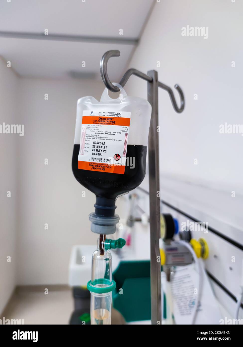 Primo piano del sacchetto di plastica per infusione endovenosa con camera di gocciolamento in sala risveglio presso l'unità di terapia intensiva dell'ospedale con sfondo bokeh. Nessuna gente. Foto Stock