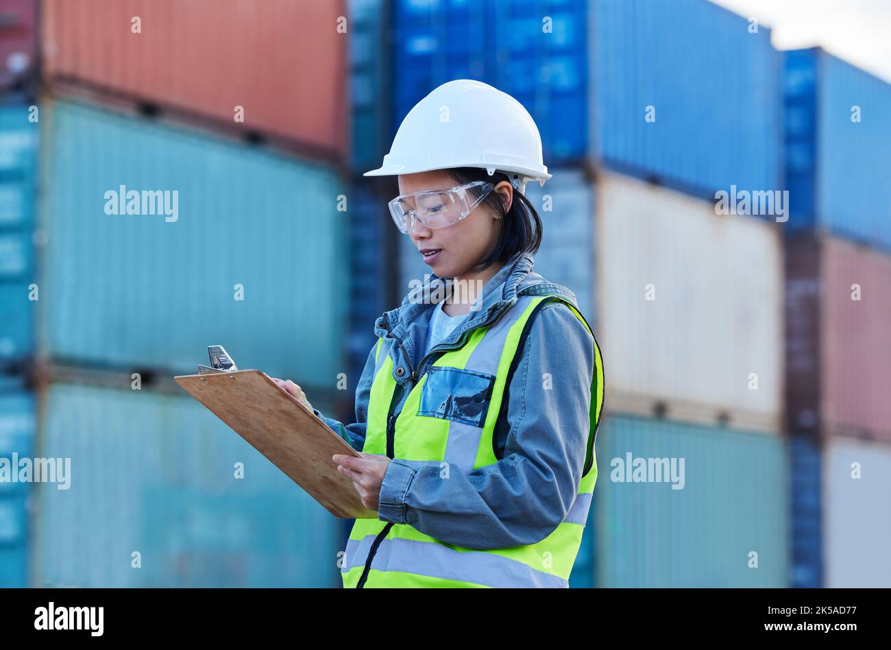 Donna lavoratore logistico, lista di controllo di spedizione e di lavoro al porto di distribuzione di container di trasporto del cantiere navale. Gestione delle scorte, supply chain per l'importazione e. Foto Stock