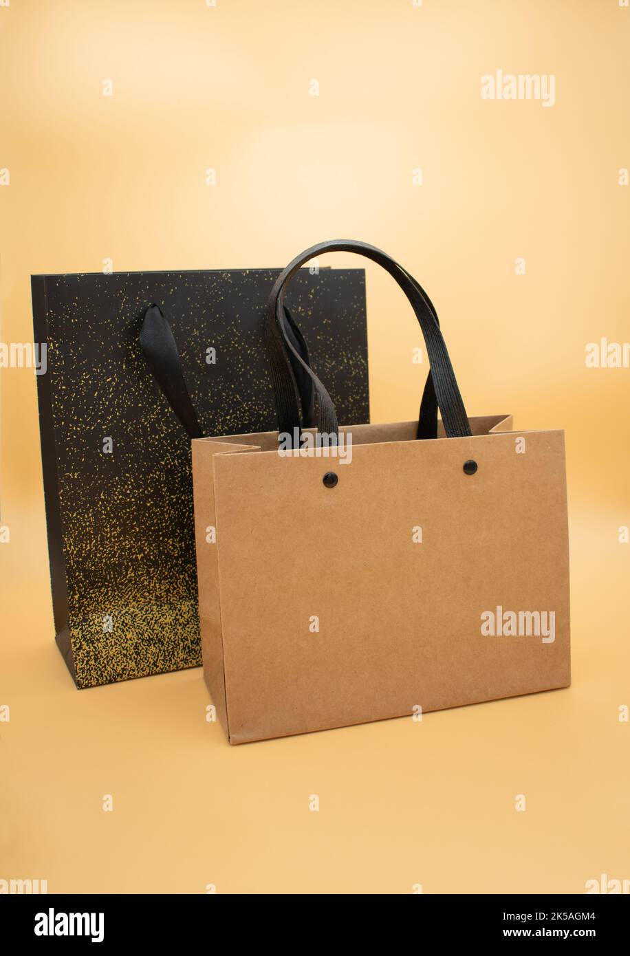 Due sacchetti di carta regalo su sfondo giallo e marrone Foto Stock